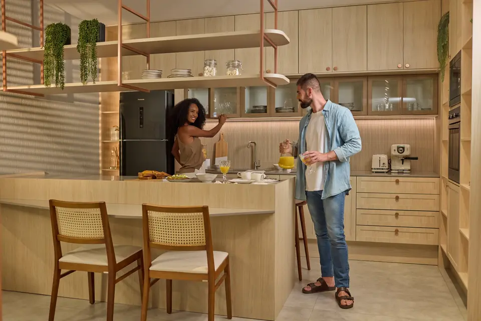 Casal em uma cozinha planejada clara com bancada e prateleiras suspensas