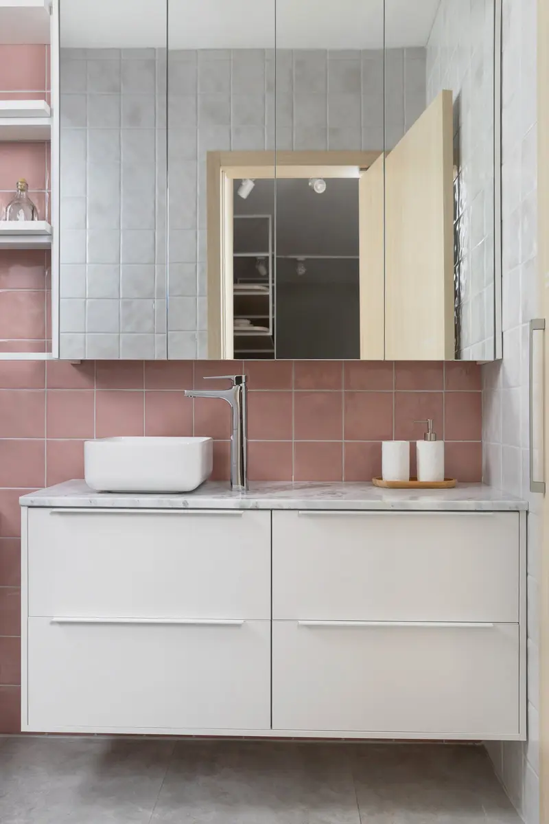 Banheiro com gabinete branco e revestimento rosa